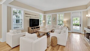 A spacious living room with a large flat-screen TV, white sofas, wooden flooring, and large windows with blinds. - Gorgeous Watercolor Home Close to  Camp with NEW 6  "LSV" Low Speed Vehicle. (SANTA ROSA BEACH)