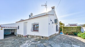 A white building with a stone-paved entrance, a satellite dish, and a small window with metal bars. - CASABLANCA. Three bedroom villa close to beaches and services in a very quiet area (Calpe)