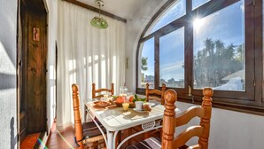 A dining area with a table set for breakfast, wooden chairs, a window with a view of palm trees, and a ceiling light. - CASABLANCA. Three bedroom villa close to beaches and services in a very quiet area (Calpe)