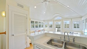 A kitchen with white cabinetry, a double sink, and a ceiling fan. - Directly Across From the Beach in Seaside + 2 Adult Bikes! (Santa Rosa Beach)