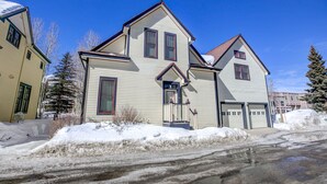Ein zweistöckiges Haus mit Garage, Veranda und einem verschneiten Einfahrt.
