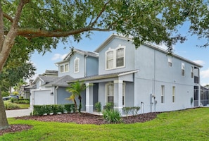 A two-story residential building with a light blue exterior, a covered front porch, and a well-maintained lawn.