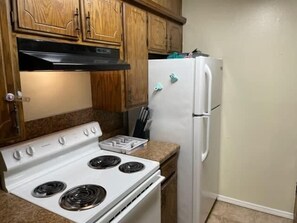 Una cocina con armarios de madera, una estufa blanca y un refrigerador blanco.