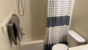 Een badkamer met een douche, toilet en handdoekhouder.