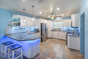 A modern kitchen with a central island, stainless steel appliances, and pendant lighting.