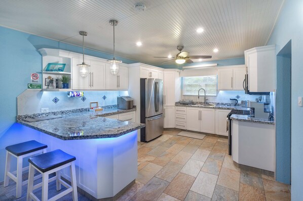 A modern kitchen with a central island, stainless steel appliances, and pendant lighting.