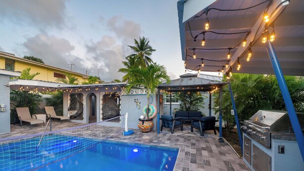 A swimming pool with lounge chairs and a barbecue area.