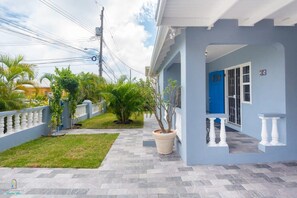 A residential property with a paved walkway, a blue door, and a potted plant.