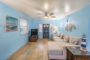 A living room with a beige sofa, a glass coffee table, a ceiling fan, and a decorative lighthouse. - Private Pool | 3 Mins to Welches Beach | BBQ (Oistins)