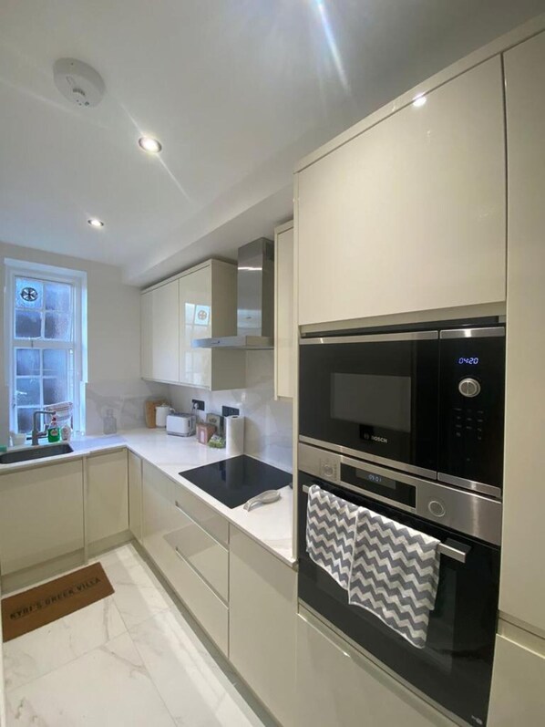A modern kitchen with white cabinetry, a Bosch microwave, and a built-in oven.
