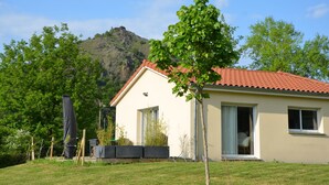 A single-story house with a red-tiled roof, a small front porch, and a garden area with a tree and a black object on the left. - Charming country house (Chamalières-sur-Loire)