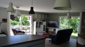 A modern living room with a large TV, a dining area, and a kitchen with a central island. - Charming country house (Chamalières-sur-Loire)