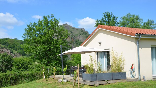 A modern house with a red-tiled roof, a patio area with a table and chairs, and a view of a mountain in the background. - Charming country house (Chamalières-sur-Loire)