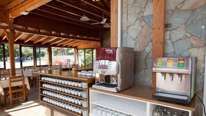 Una cafetería con interior de madera, una máquina de café y una variedad de tazas y vasos de café exhibidos en estanterías.