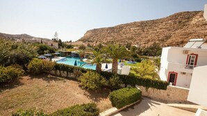 Un área de piscina con varias piscinas, rodeada de palmeras y follaje, con montañas al fondo.