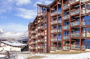 A multi-story hotel with balconies, a ski resort in the background, and a sign for 'Supermarché shepa'. - 10m from resort center, 2nd floor, view valley, balcony, tv, 33m², Les Arcs (Les Arcs)