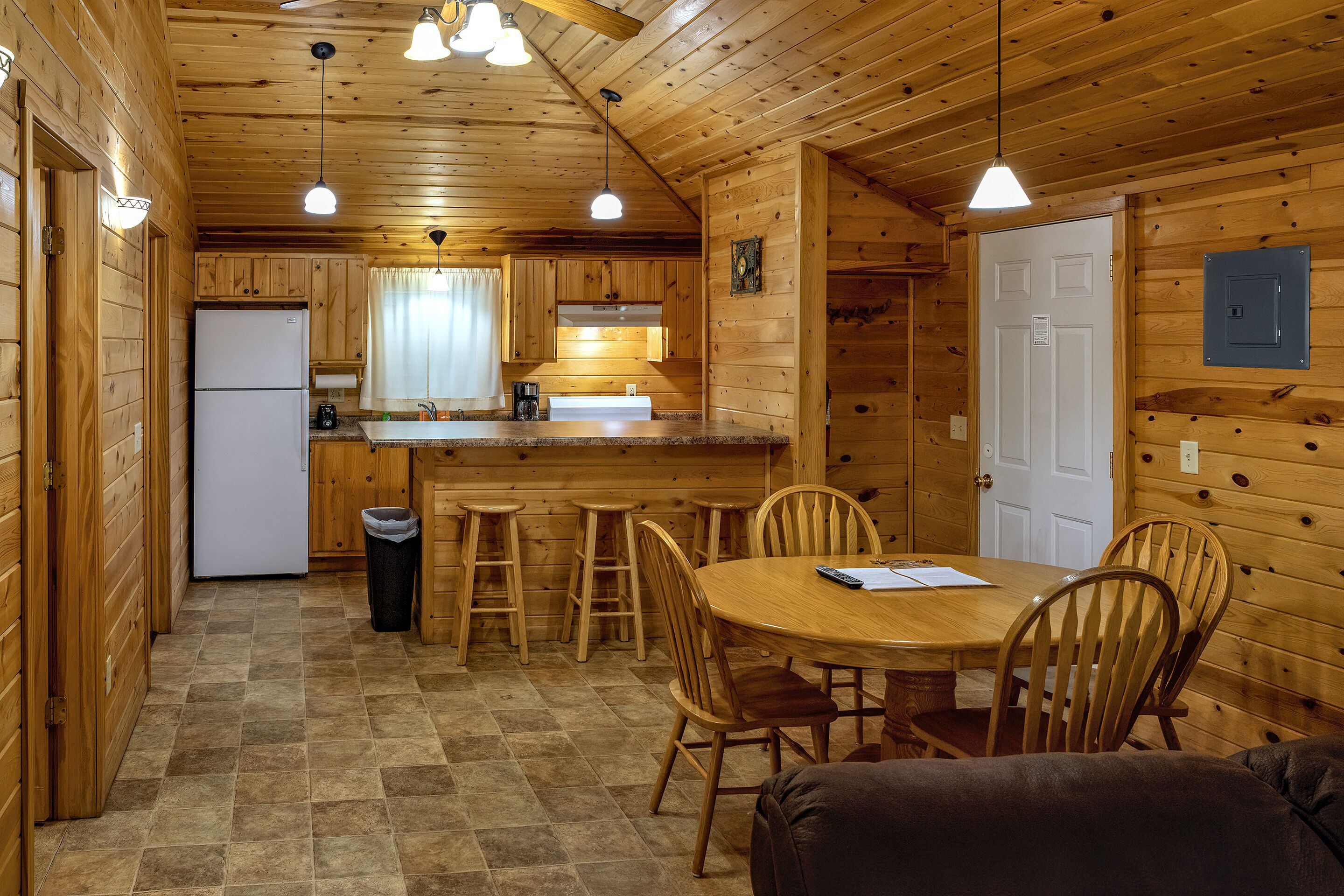 A wooden cabin with a kitchen, dining area, and a white door.