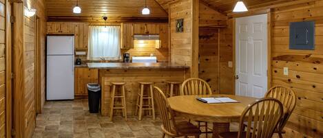 A wooden cabin with a kitchen, dining area, and a white door.
