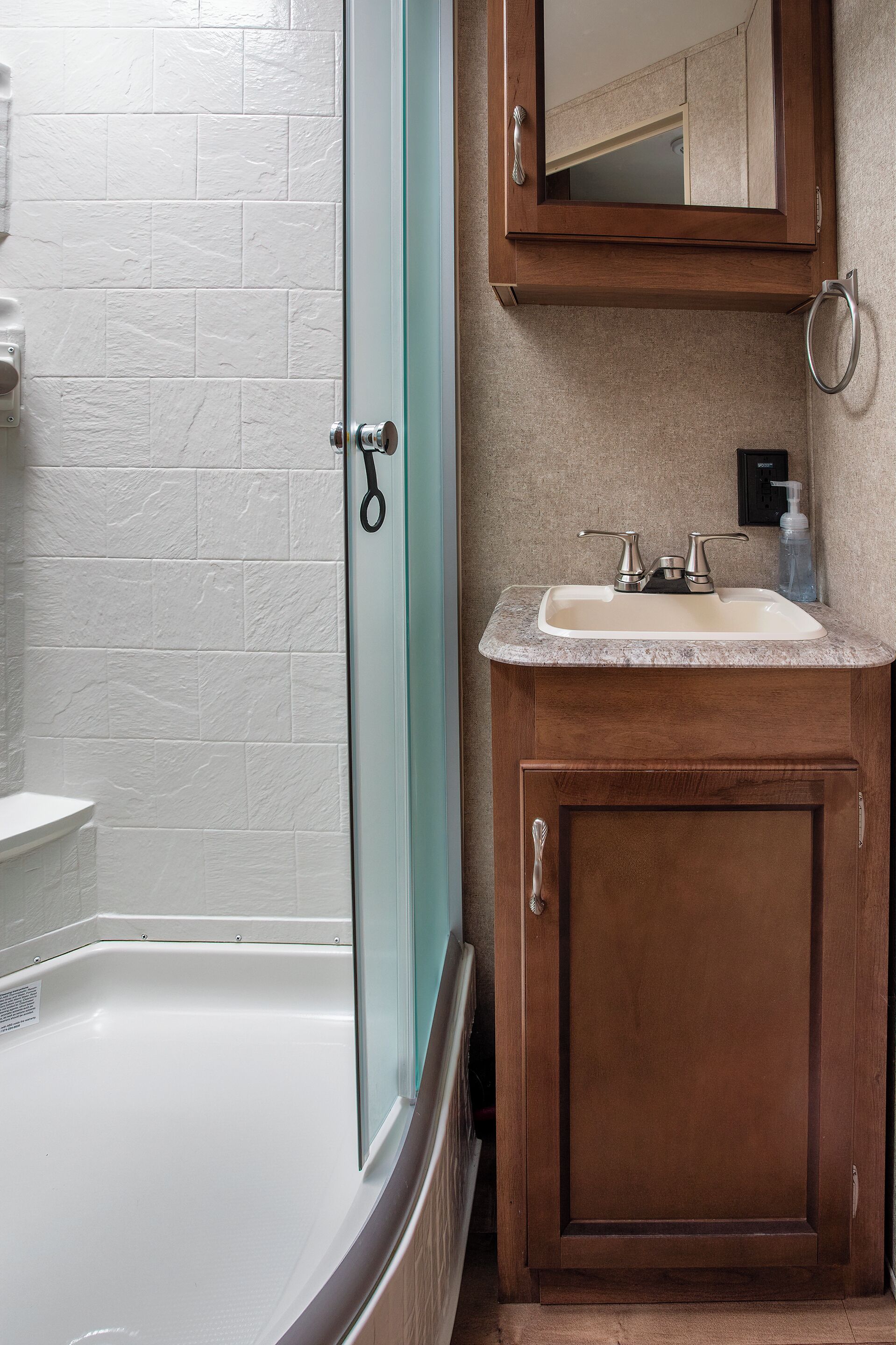 Un baño con una bañera blanca, un tocador de madera con un lavabo y un espejo sobre el lavabo.