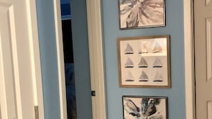 Un pasillo con paredes azules, molduras blancas y tres obras de arte enmarcadas.