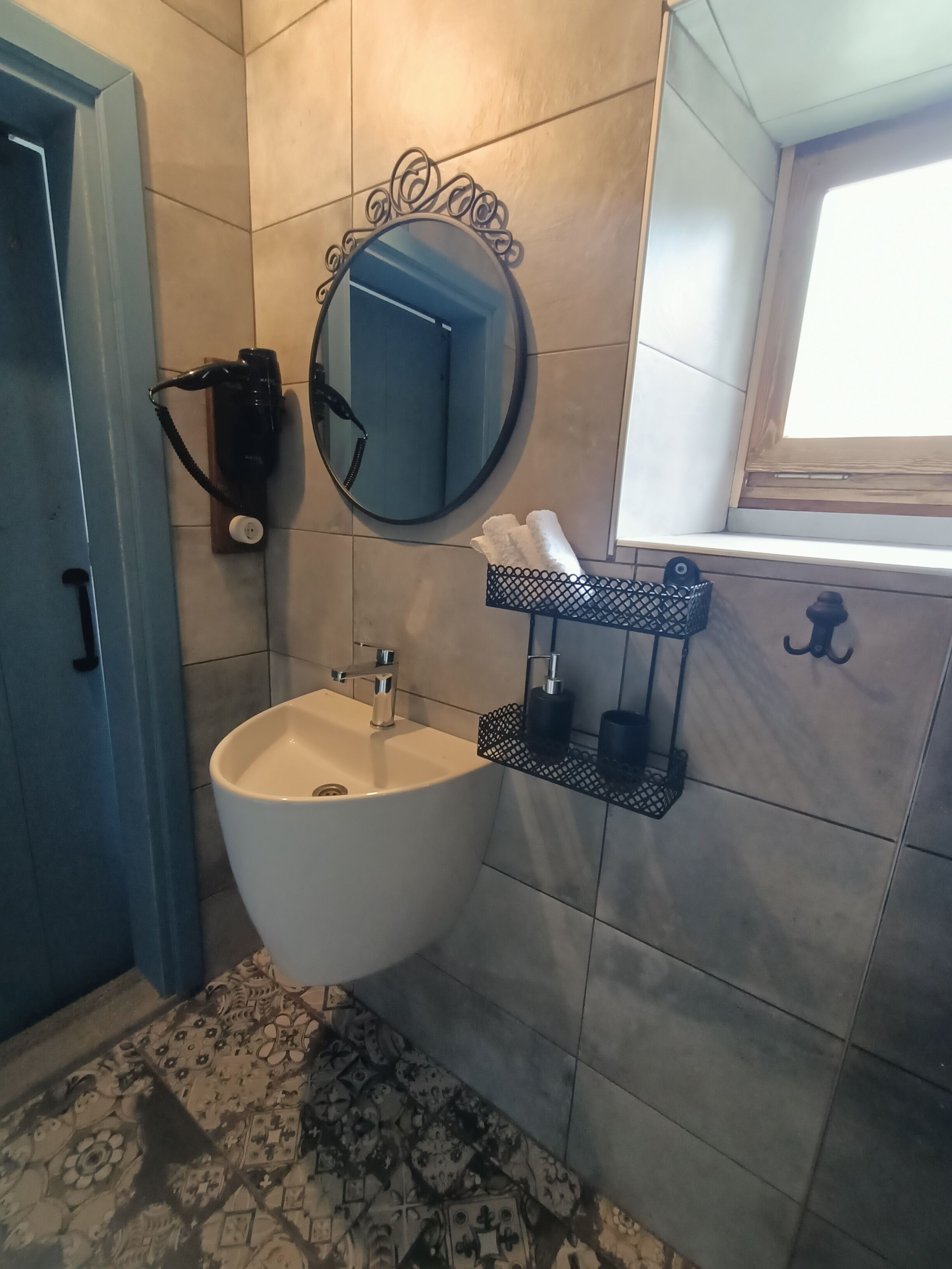 Une salle de bain avec un lavabo blanc, un miroir et une fenêtre.