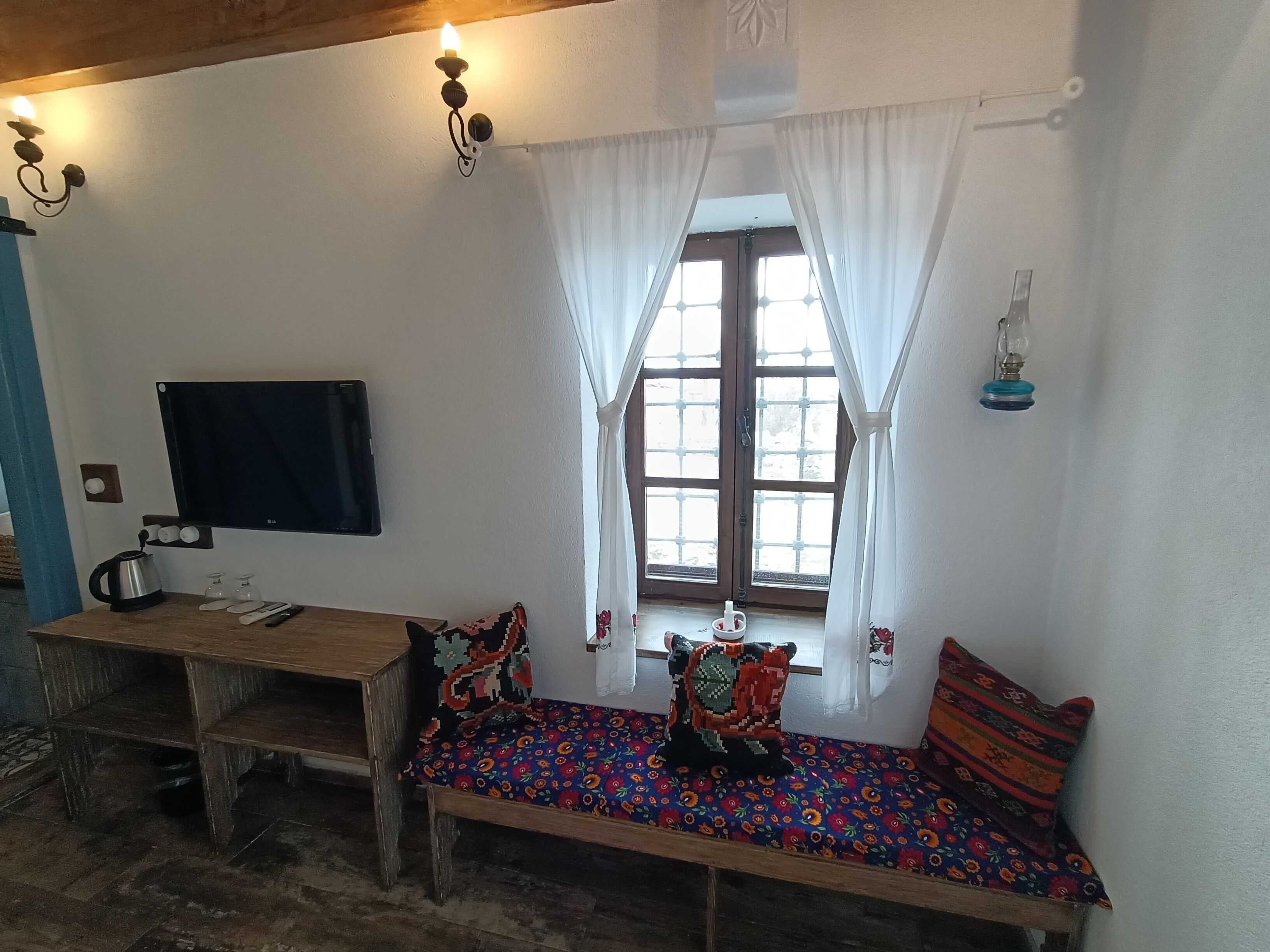 Una habitación acogedora con un banco de madera, un televisor y una ventana con cortinas.