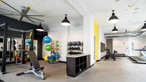 Une salle de sport équipée de matériel d’exercice, dotée d’un ventilateur au plafond et d’un tapis de course.