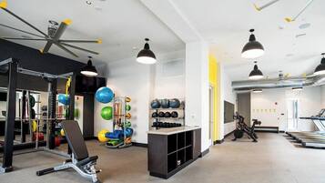 A gym with exercise equipment, a ceiling fan, and a treadmill.