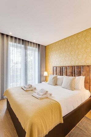 A hotel room with a large bed, a headboard, and a window with curtains. - Almada Downtown Apartment by DA'Home (Porto)