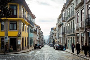 A cobblestone street lined with multi-story buildings, some with balconies and signage. - Almada Downtown Apartment by DA'Home (Porto)
