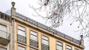 En bygning med flere etager, en gul facade, flere balkoner og store vinduer.