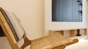En moderne stue med en træstol, et stort fladskærms TV monteret på væggen og et minimalistisk design.