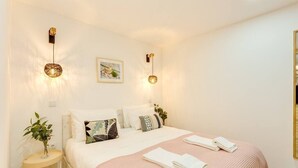 A neatly made bed with a pink blanket, two bedside tables with plants, and wall-mounted lights. - *NEW* Riverside 2 Bedroom Apartment by DA'HOME (Porto)