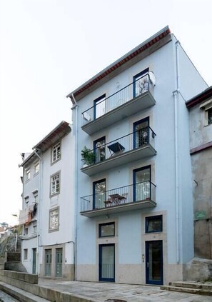 Un edificio de varios pisos con balcones, una escalera y una puerta.