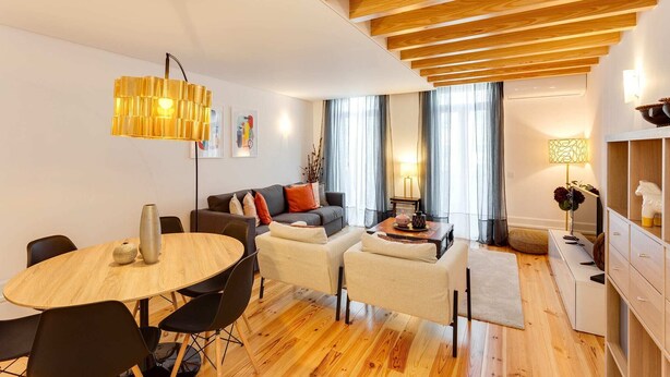 Een moderne woonkamer met een houten plafond, een ronde eettafel en een bank.