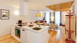 Een moderne keuken met een ingebouwde oven en vaatwasser, een eetgedeelte met een tafel en stoelen, en een woonkamer met een bank en salontafel.
