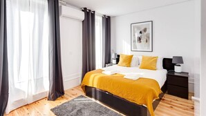 Een moderne slaapkamer met een bed, nachtkastjes, een vloerkleed en gordijnen.