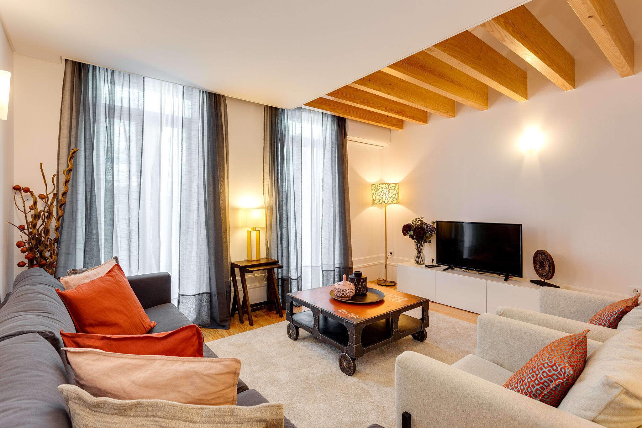 A modern living room with a sofa, armchairs, a coffee table, and a television.