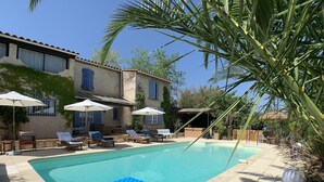 A swimming pool with lounge chairs and umbrellas, surrounded by a building with a tiled roof and a covered seating area. - Gite in Maison d'hôtes in Pays de Fayence - 3 bedrooms Swimming pool, Jacuzzi (Tourrettes)