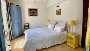 A bedroom with a bed, two bedside lamps, a ceiling fan, a wardrobe, a chair, and two paintings on the wall. - Gite in Maison d'hôtes in Pays de Fayence - 3 bedrooms Swimming pool, Jacuzzi (Tourrettes)