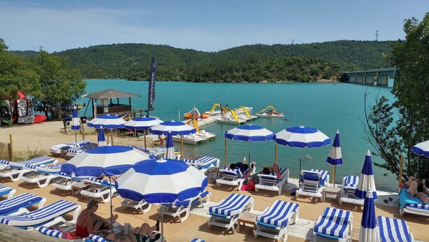 A beach with sun loungers and umbrellas, a water slide, and a forested hill in the background. - Gite in Maison d'hôtes in Pays de Fayence - 3 bedrooms Swimming pool, Jacuzzi (Tourrettes)
