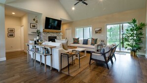A spacious living room with a fireplace, a television, and a large window offering a view of the outdoors.