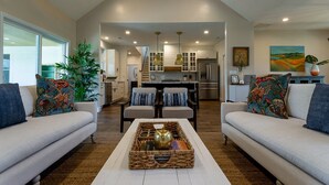 A spacious living room with two sofas, a coffee table, and a kitchen in the background.