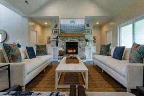 A living room with two sofas, a coffee table, a fireplace, and a sign above the fireplace.