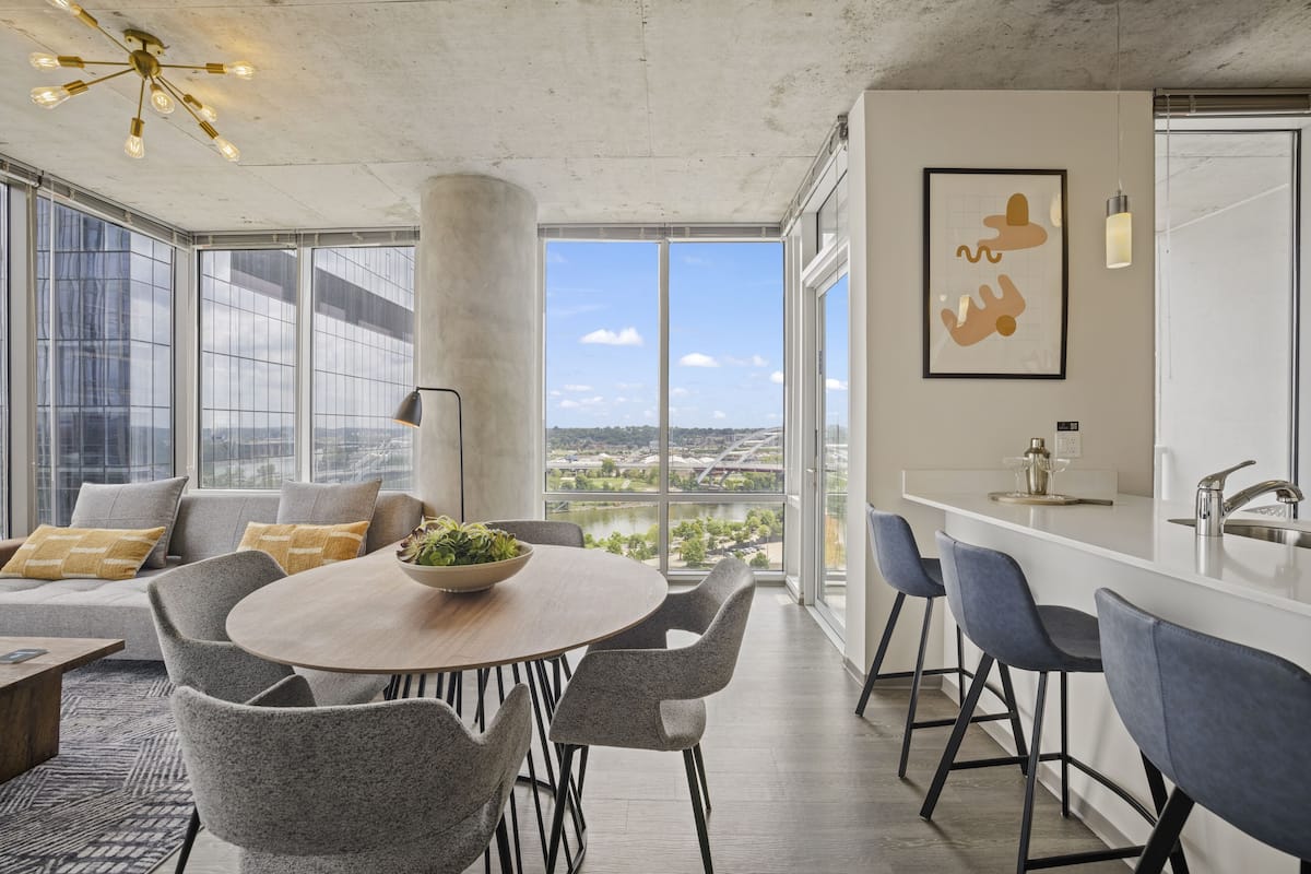 A modern kitchen with a large island, bar stools, and a view of the city.