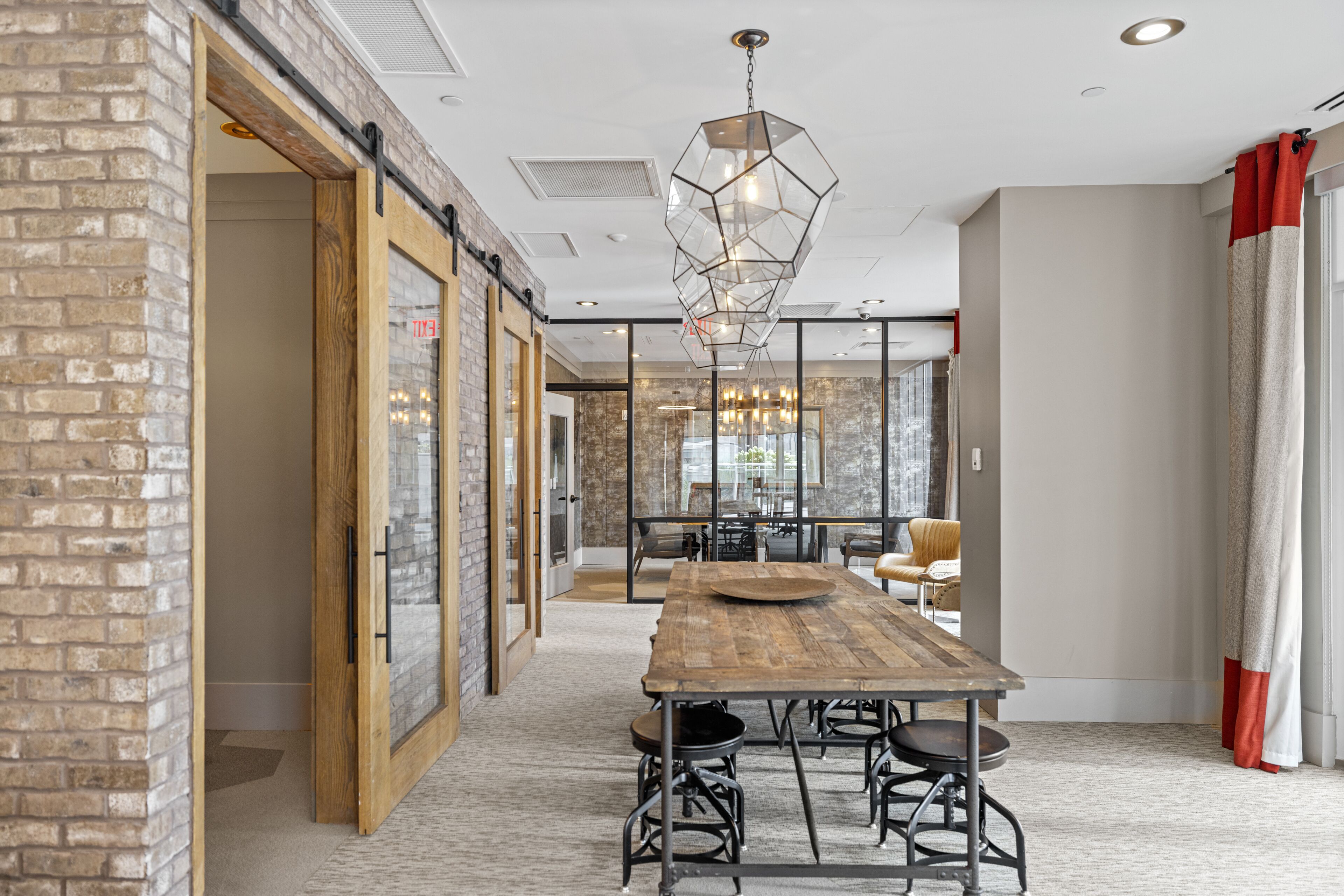 A spacious room with a long wooden table, comfortable seating, and a modern chandelier.