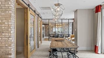 A spacious room with a long wooden table, comfortable seating, and a modern chandelier.