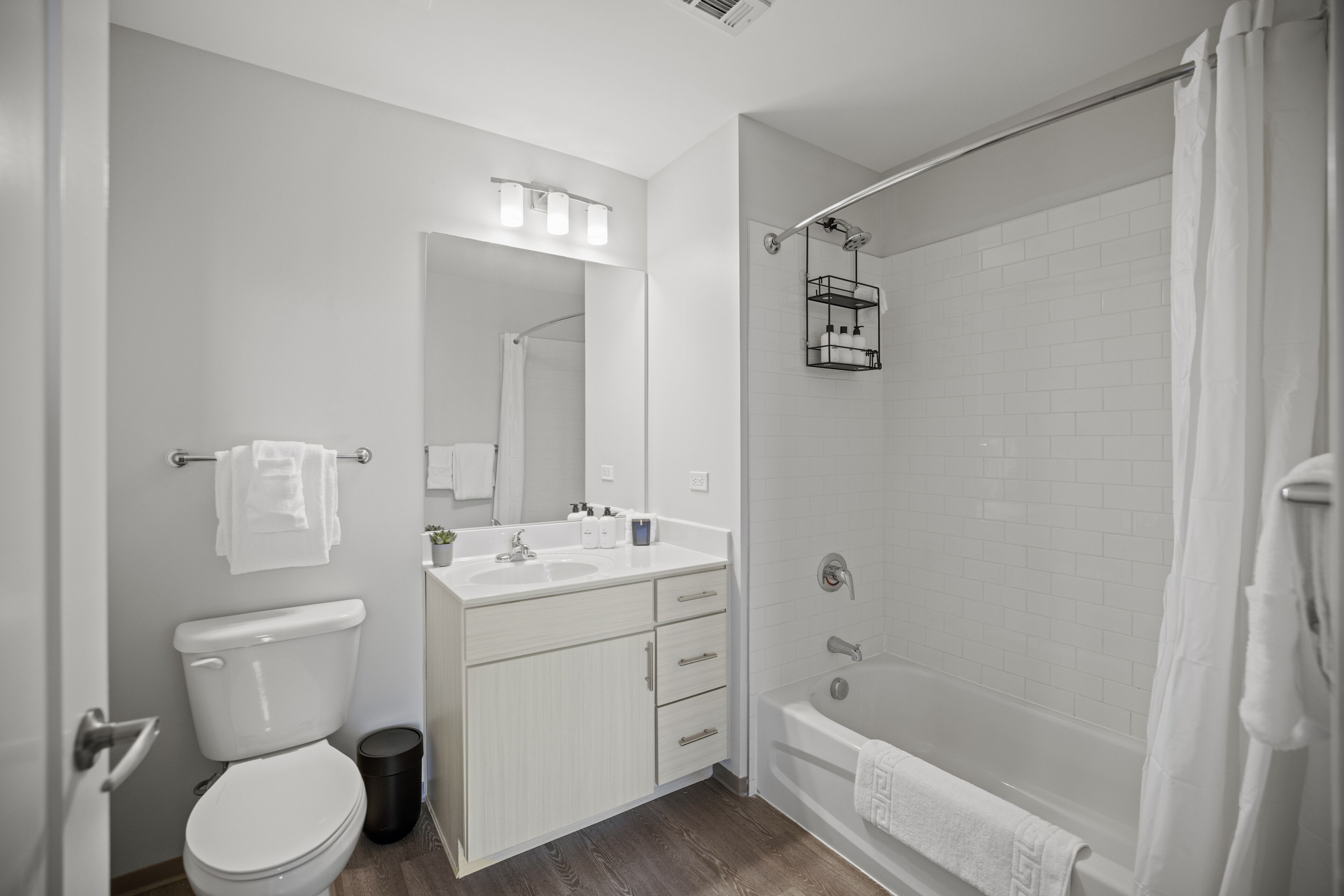 A modern bathroom with a toilet, sink, vanity, and bathtub.