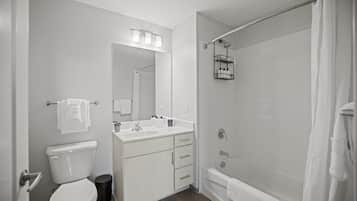 A modern bathroom with a toilet, sink, vanity, and bathtub.