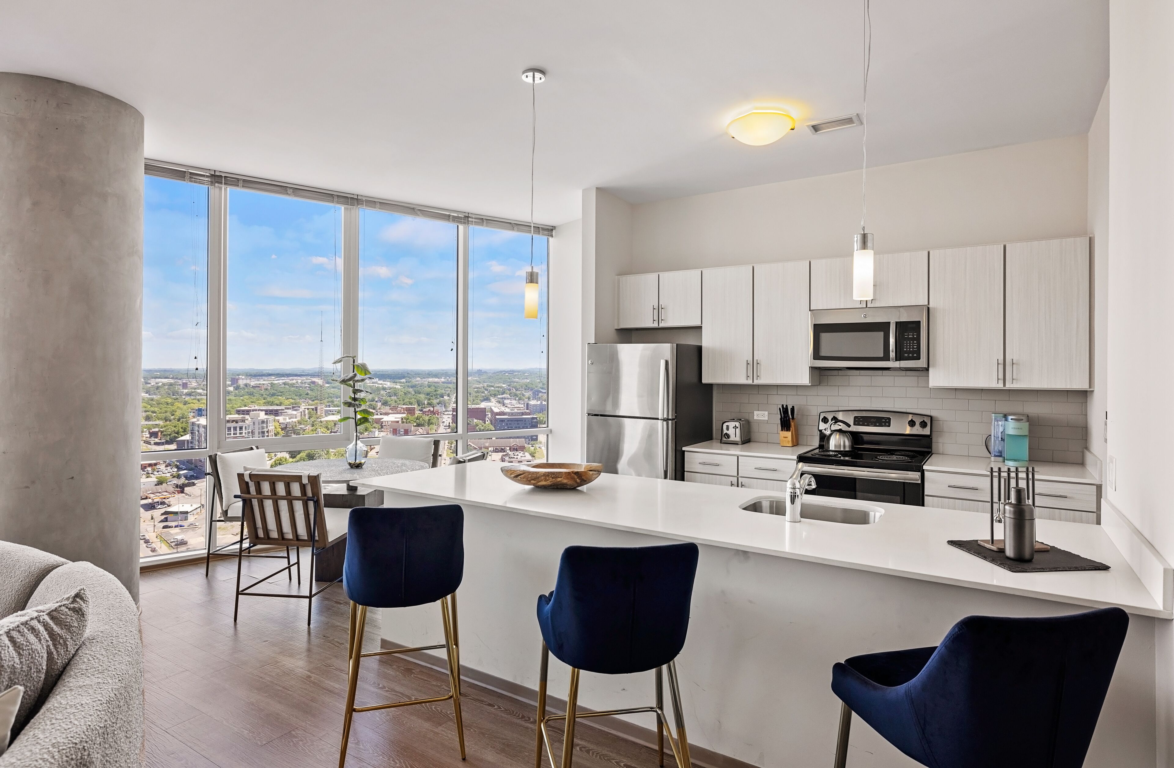 A modern kitchen with a large island, bar stools, and a view of the city.